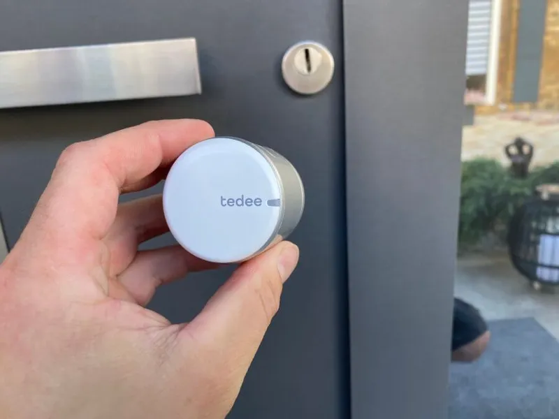 Hand dreht das Tedee Smartlock am Türzylinder einer anthrazitfarbenen Haustür