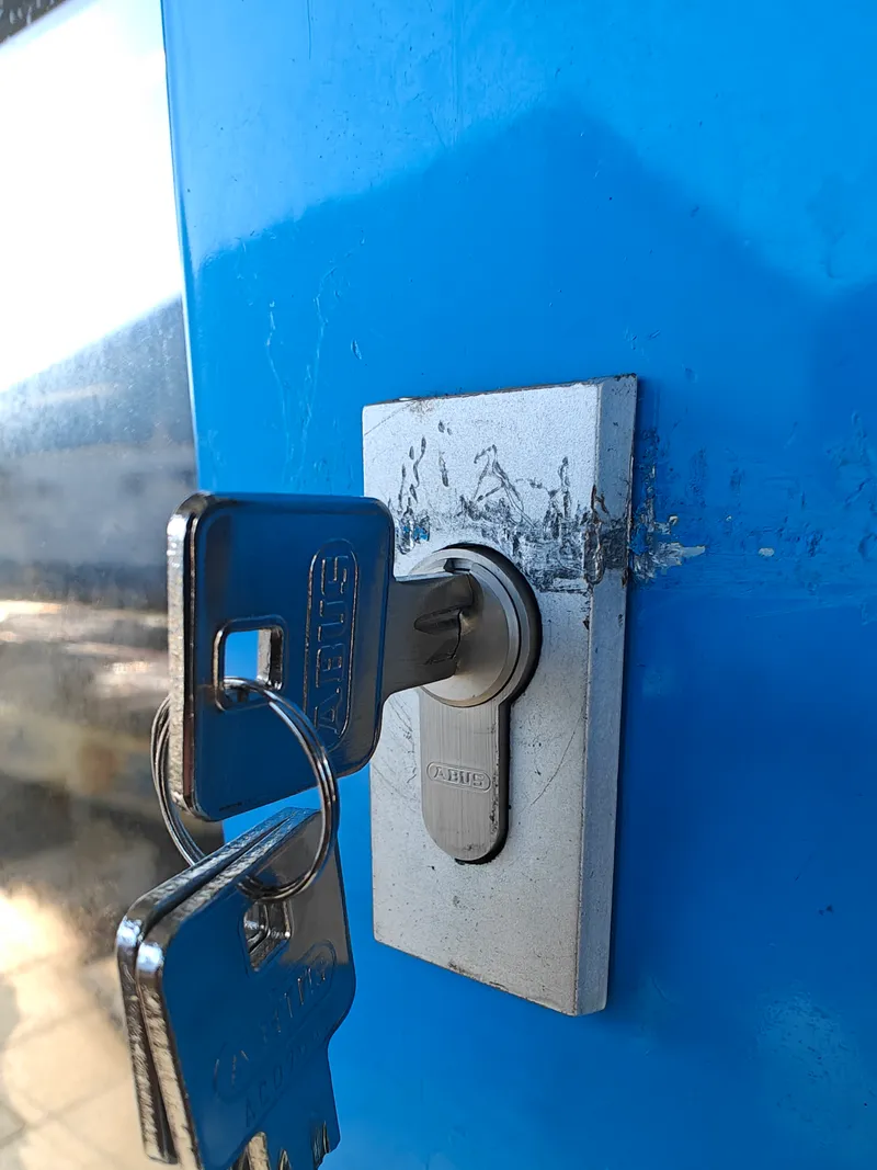 Profilzylinder in einer blauen Tür mit steckendem Schlüssel und Schlüsselbund
